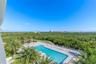 Swimming pool featuring a paved deck, perimeter fencing, palm tree landscaping, and coastal cityscape backdrop