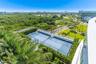 Hard-surface tennis court featuring perimeter chain-link fencing and lush vegetation border