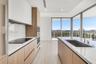 Kitchen featuring wood-finish flat-panel cabinetry, white stone countertops, matching full-height backsplash, built-in stainless steel appliances, and