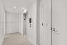 Hallway featuring light-toned wood-finish flooring, recessed ceiling lighting, and a dedicated elevator access point with a metallic call button panel