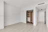 Room featuring neutral wall finishes, light wood-finish flooring, and a built-in closet system with integrated shelving and drawer storage behind a sl
