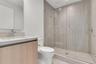 Bathroom featuring a wood-finish vanity with a stone countertop, an integrated sink, polished chrome plumbing fixtures, and a glass-enclosed shower wi