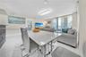 Open-concept living space featuring high-gloss tile flooring, floor-to-ceiling sliding glass doors, and a rectangular, modern tiered crystal ceiling f