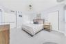 Spacious room featuring glossy tile flooring, dual closets with bi-fold doors, and a decorative multi-arm chandelier