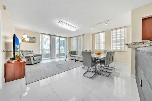 Open-concept living space featuring high-gloss tile flooring, floor-to-ceiling glass doors, built-in breakfast bar, contemporary crystal chandelier, a