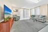 Open-concept living space featuring high-gloss tile flooring, floor-to-ceiling vertical blinds, and a modern crystal flush-mount light fixture