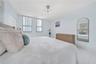 Bright room featuring light-toned flooring, multi-pane windows with vertical blinds, a contemporary sputnik-style chandelier, and an arched wall-mount