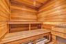 Sauna featuring natural wood tongue-and-groove paneling, tiered wood bench seating, and a built-in heating element