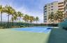 Hard-surface tennis court featuring perimeter privacy fencing and palm tree landscaping