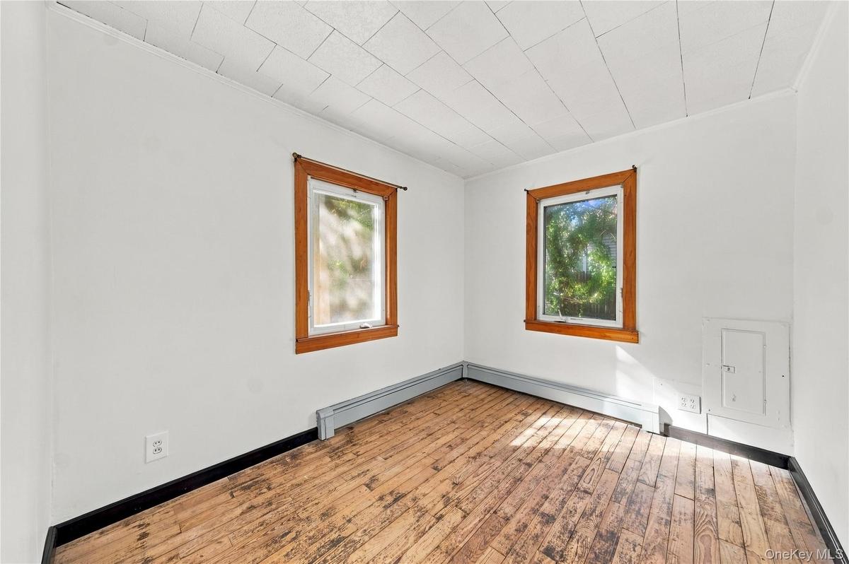 Wood-finish flooring, two windows with natural wood trim, freshly painted