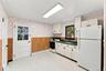 Kitchen featuring white cabinetry, solid-surface countertops, paneled wainscoting, and direct exterior access
