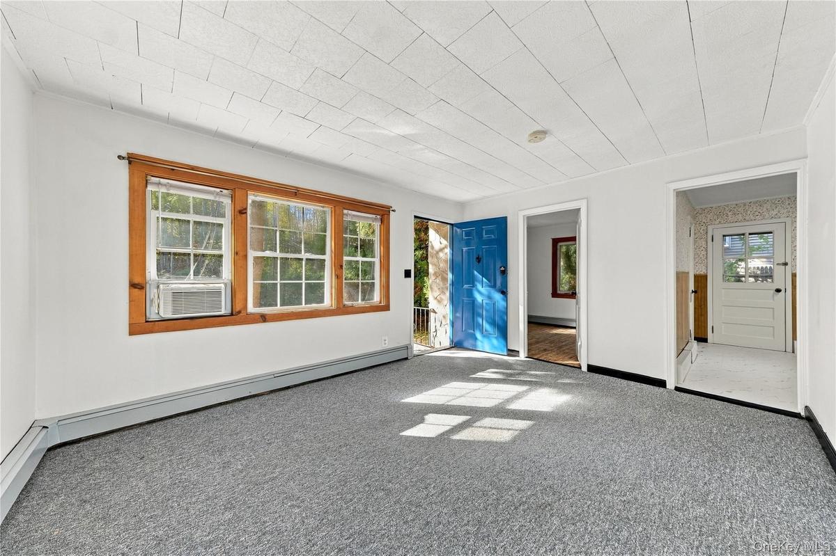 Room featuring neutral carpeting, multi-pane windows with wood trim, a paneled blue entry door, freshly painted