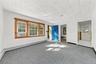 Room featuring neutral carpeting, multi-pane windows with wood trim, a paneled blue entry door, freshly painted