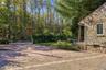 Stone veneer exterior with a multi-toned brick paver driveway and mature perimeter trees