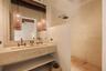 Stone-topped double vanity featuring an integrated trough sink, wall-mounted bronze-finish faucets, large rectangular mirror, and textured pendant lig