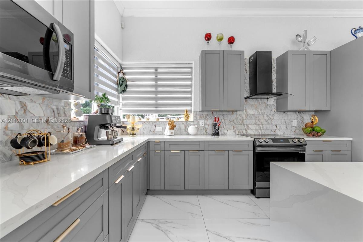 Kitchen featuring shaker-style cabinetry, white countertops, stone-patterned backsplash, large-format tile flooring, and stainless steel appliances