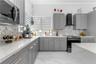 Kitchen featuring shaker-style cabinetry, white countertops, stone-patterned backsplash, large-format tile flooring, and stainless steel appliances