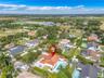 Aerial perspective featuring a single-story residence with a multi-hipped terracotta tile roof, an in-ground swimming pool, concrete paved patio area,