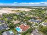 Aerial perspective featuring a terracotta-tiled roof, rectangular swimming pool, integrated spa, and concrete driveway on a landscaped lot