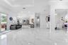 Open-concept main living area featuring large-format polished tile flooring, recessed lighting, tray ceilings, and a glass-paneled door leading to an 