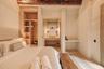 Exposed wooden ceiling beams, integrated wood-finish shelving, natural stone vanity, pendant lighting, and stone flooring