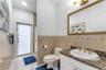 Bathroom featuring stone-finish countertop, undermount sink with gold-tone hardware, decorative tiled wall accent, glass-enclosed shower, and opaque-p