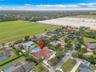 Aerial perspective of a property featuring a multi-hipped tile roof, an expansive paved driveway, and a private rear swimming pool