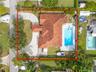Aerial perspective featuring a tile roof, concrete driveway, in-ground swimming pool, and landscaped perimeter hedging
