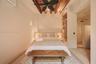 Exposed wood ceiling beams, built-in wooden shelving, wall-mounted air conditioning unit, and matte black ceiling fan