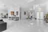 Open-concept interior featuring large-format stone-finish tile flooring, recessed ceiling lighting, a modern spiral chandelier, and an arched window