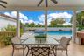 Covered patio featuring tiled flooring, structural columns, ceiling fans, and a tiled swimming pool with an integrated spa
