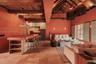 Open-concept living space featuring vaulted ceilings with exposed wood beams, stone tile flooring, a built-in kitchen island with integrated shelving,