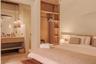 Built-in wood shelving, custom floor-to-ceiling wardrobe, stone-surfaced vanity with dual basins, and pendant lighting