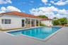 Single-story residence featuring a tile roof, covered patio with structural columns, and an integrated in-ground pool with an attached spa