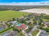 Aerial perspective of a sprawling property featuring a multi-gabled terracotta tile roof, a rectangular swimming pool, an expansive paver driveway, an