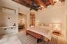 Exposed timber ceiling beams, integrated wood-finish wardrobe cabinetry, neutral stone-finish flooring, and wall-mounted ductless climate control unit