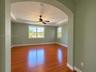 Interior space featuring wood-finish flooring, a tray ceiling with a center-mounted ceiling fan, and multi-lite windows framed by arched doorways