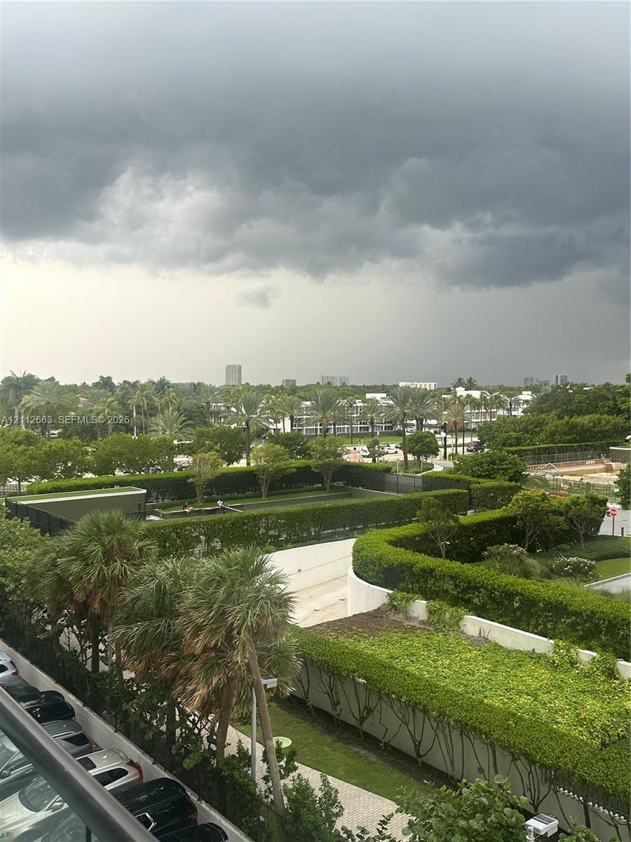 Exterior grounds featuring manicured hedges, mature palm trees, paved walkways, and a fenced recreation area