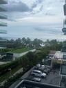 Balcony featuring glass railings and an expansive horizon line including ocean and coastal greenery