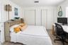 Room featuring wood-finish flooring, two sets of white paneled bifold closet doors, and plantation shutters