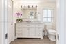 White shaker-style vanity with stone-top surface and undermount sink, multi-drawer cabinetry, chrome five-bulb vanity light fixture, and wood-finish f