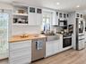 Kitchen featuring white shaker-style cabinetry, wood-finish countertops, stainless steel farmhouse sink, glass-front upper cabinet doors, and wood-fin
