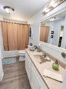 Bathroom featuring wood-finish flooring, a white vanity with an integrated sink and solid-surface countertop, a polished chrome single-lever faucet, a