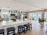 Kitchen featuring a white quartz island countertop, stainless steel appliances, white cabinetry with glass-front uppers, stacked stone accent wall, an