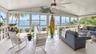 Screened lanai featuring large-format ceramic tile flooring, a vaulted ceiling with a central paddle fan, and an expansive wall of floor-to-ceiling wi