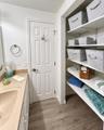 Solid surface vanity with an integrated basin, wood-finish flooring, and built-in adjustable shelving