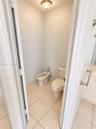 Water closet featuring a two-piece toilet, bidet, neutral tile flooring, and a flush-mount ceiling light fixture