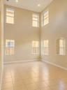 Double-height ceilings featuring recessed lighting, large-format tile flooring, and multiple window placements including a signature arched window