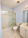 Bathroom featuring a tub-shower combination with glass sliding doors, ceramic tile shower surround, vanity with an integrated sink, and large wall-mou
