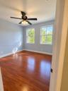 Room featuring wood-finish flooring, dual windows with muntins, and a ceiling fan with integrated lighting